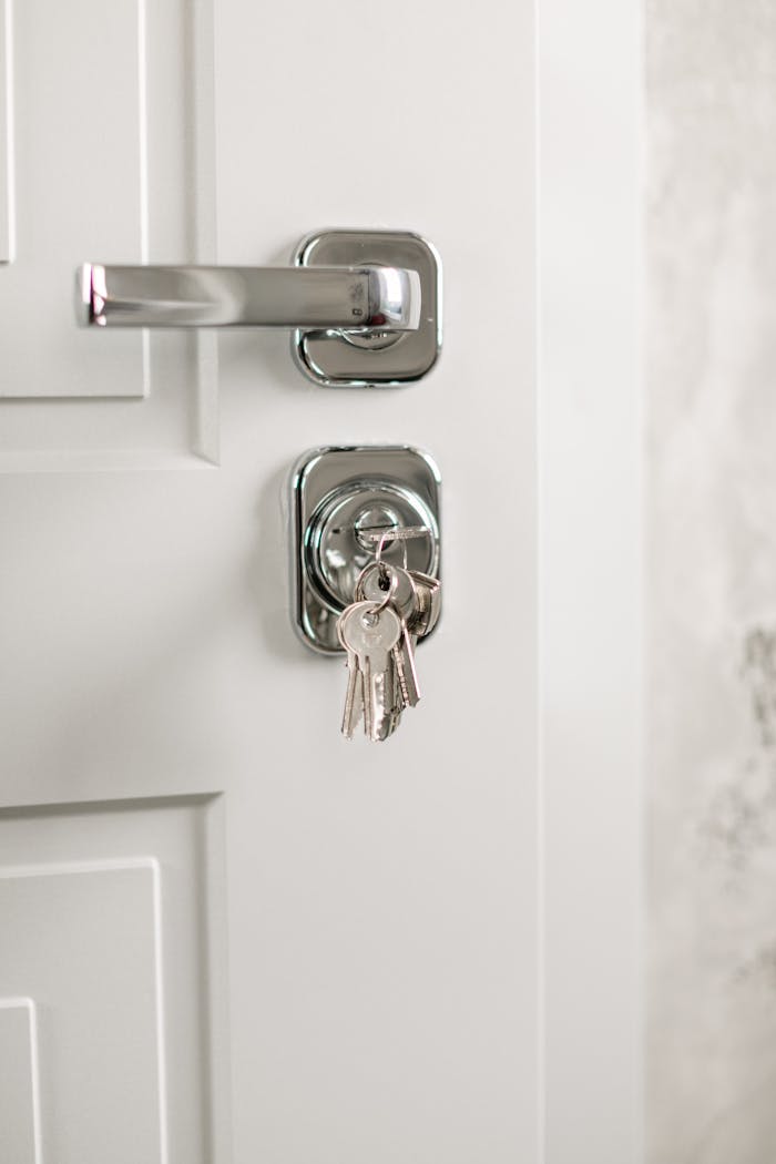 portfolio-06 Close-up of a modern silver door handle with keys hanging in the lock, symbolizing security.