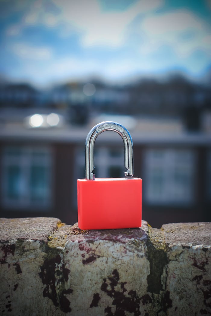 why-choose-us A vibrant red padlock on a stone ledge with a blurred urban background, symbolizing security.