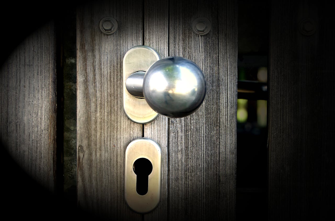 portfolio-03 Close-up view of a metal doorknob and keyhole on a wooden gate, emphasizing security and design.